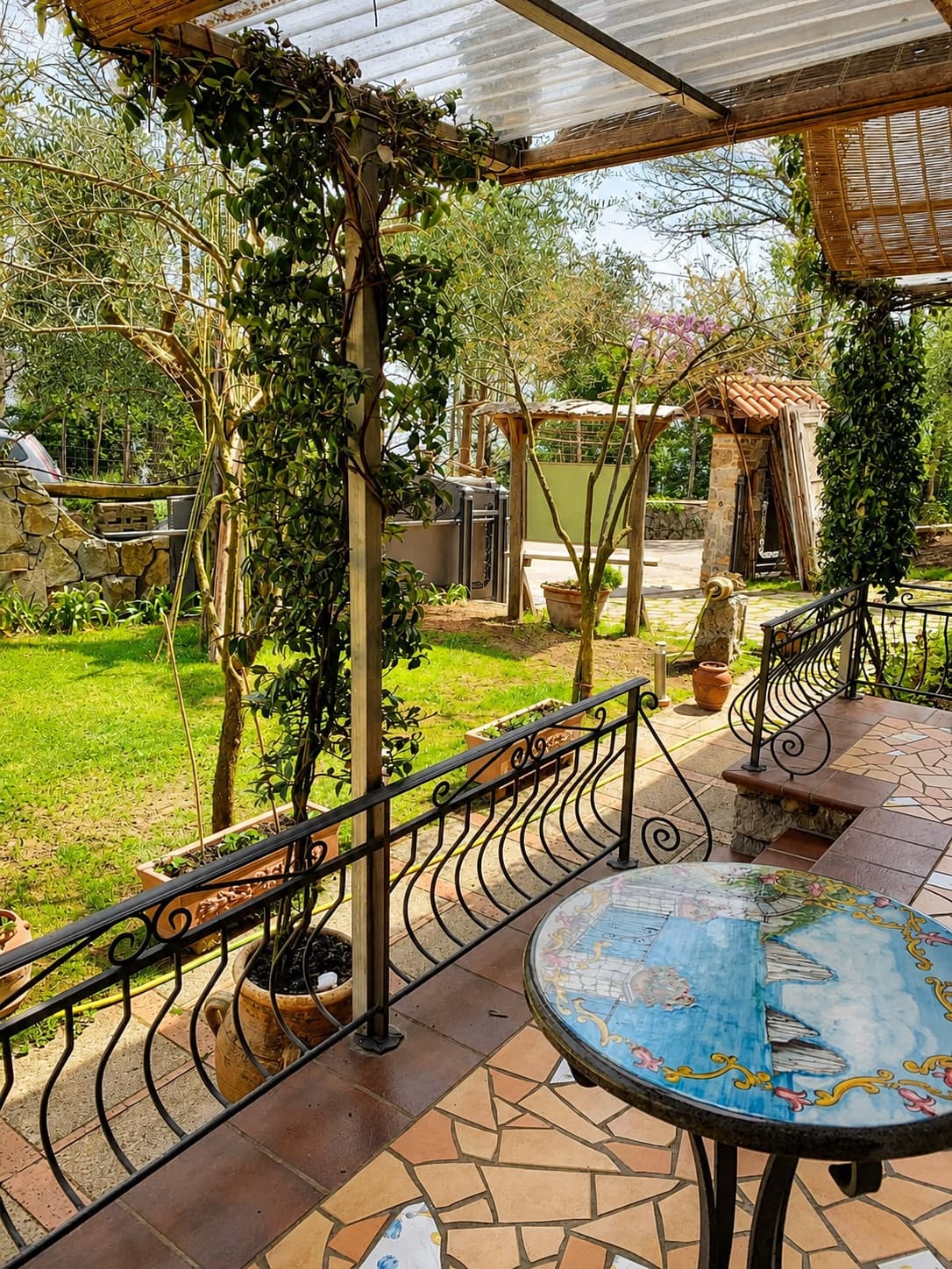 The vine-covered pergola outside, with a hand-painted table and the lawn beyond